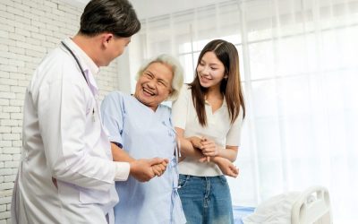 Smiling,Elderly,Woman,In,A,Hospital,Gown,Holding,Hands,With